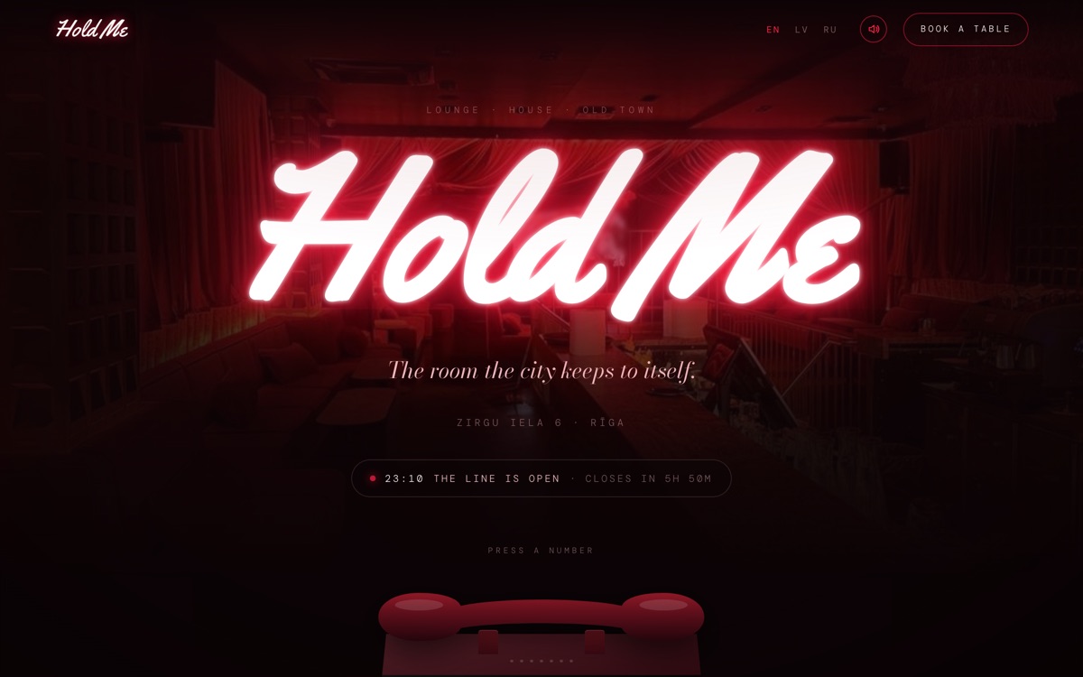 Hold Me bāra un kluba mājaslapa datora ekrānā ar ēdienkartēm un darba laiku